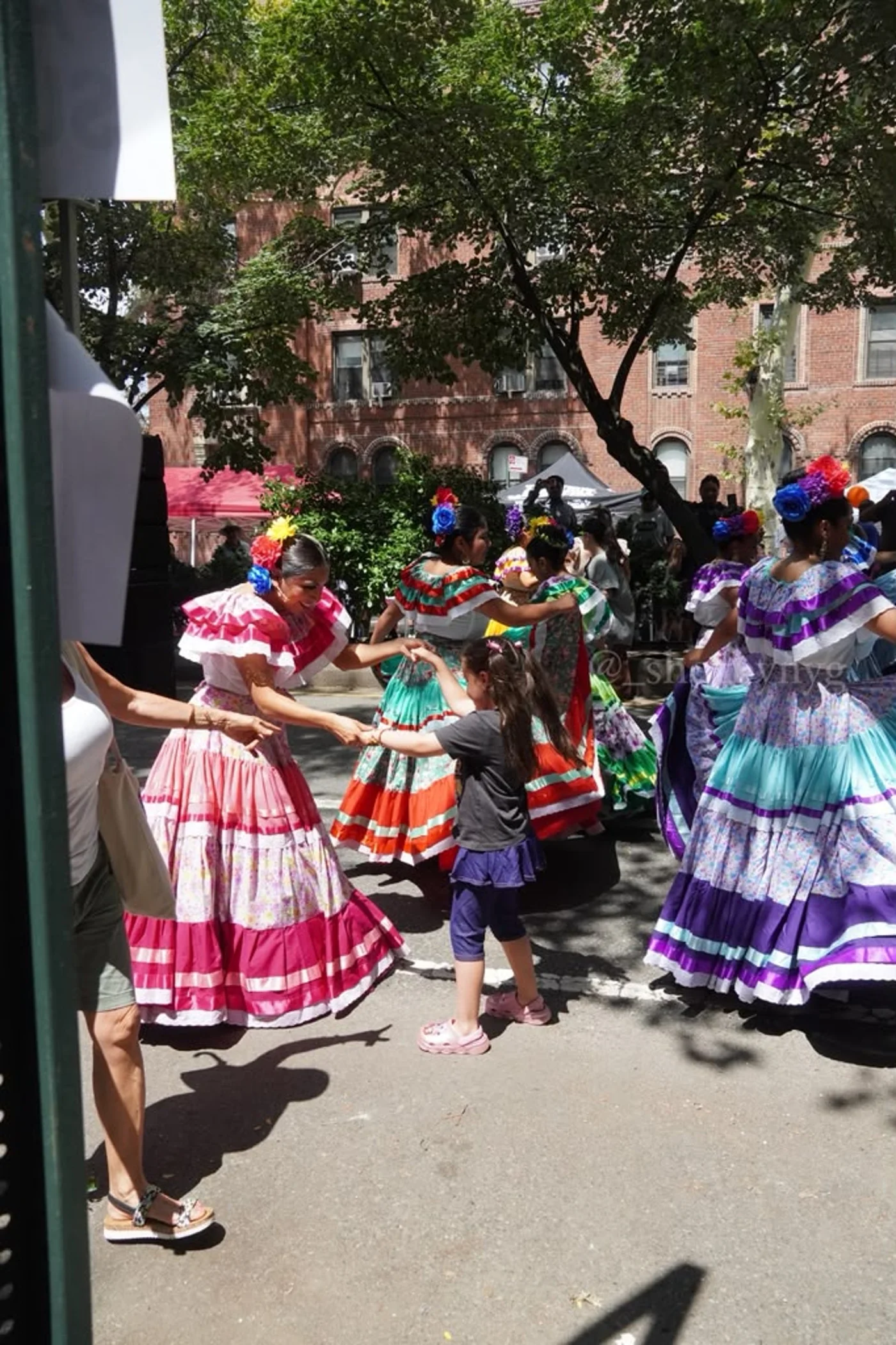 A child joins folkloric dancers during Jackson Heights Day